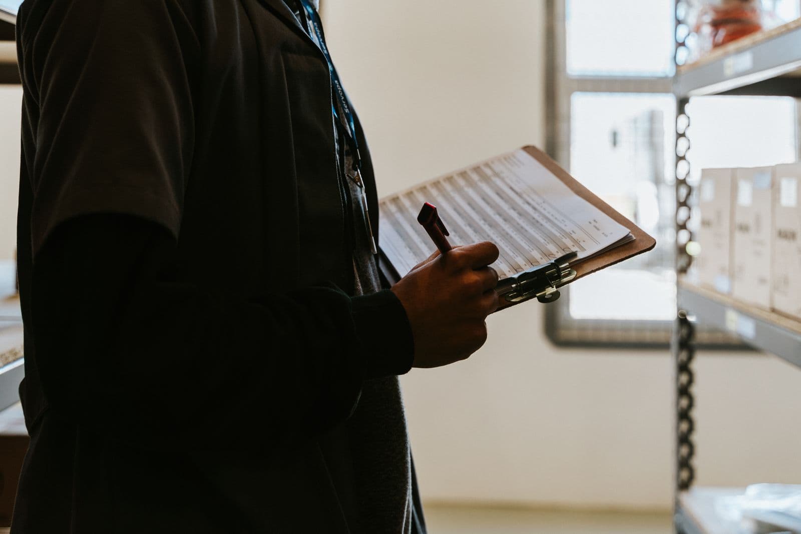 A warehouse worker reviewing an inventory checklist on a clipboard