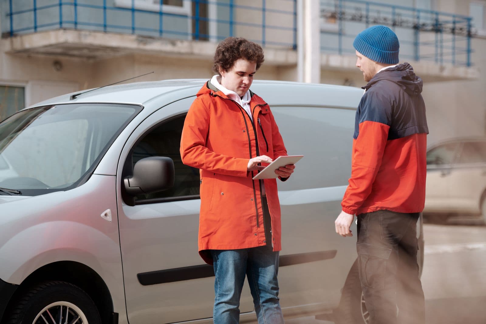 A delivery driver using a digital tablet beside their van to manage an order