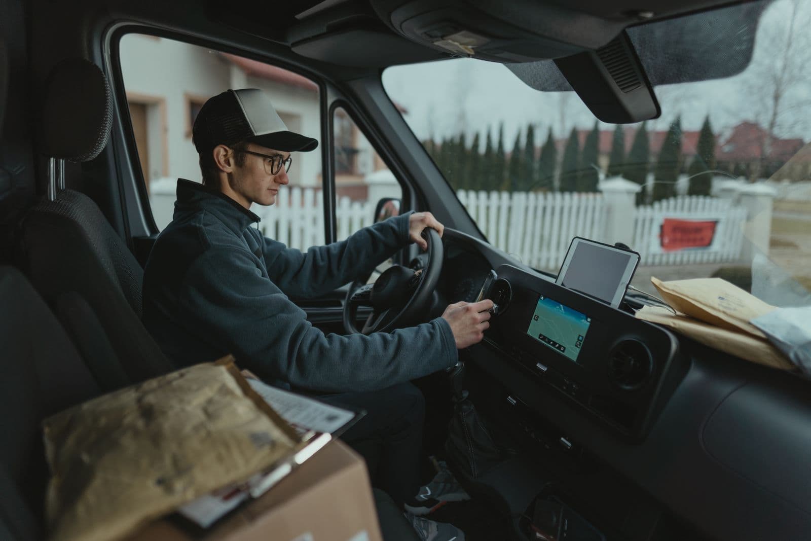 A delivery van driver checks a GPS navigation screen while en route with parcels