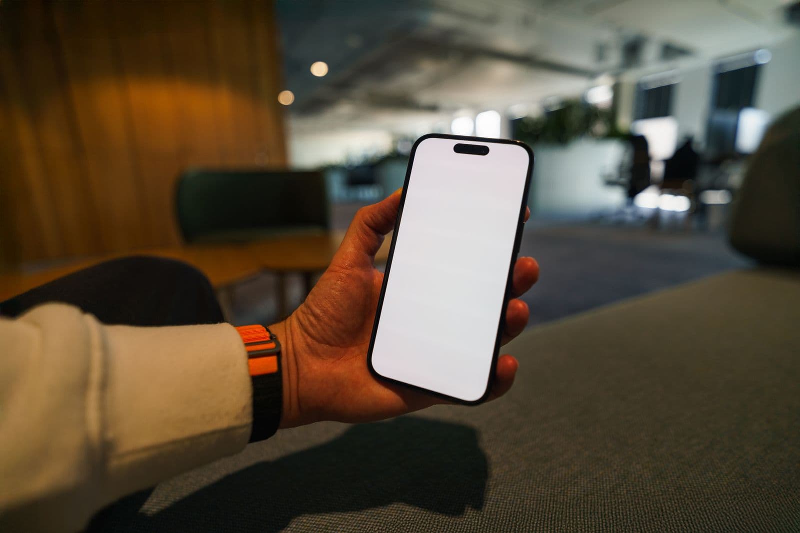 A hand holding a smartphone with a blank screen, ready for custom branding