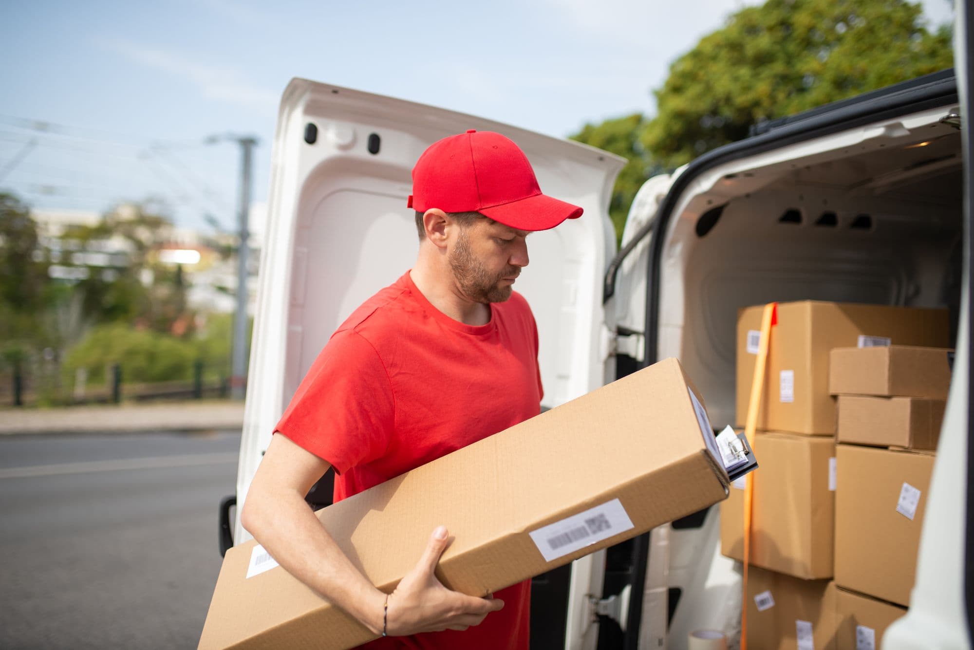 A courier loading multiple labeled packages into a delivery van